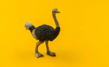 Plastik devekuşu oyuncak sarı bir arka plan üzerinde. Hayvanlarıyla bir çocuk için. Kopya alanı.