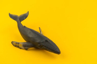 Sarı bir arka plan üzerinde plastik oyuncak balina. Deniz hayvan bir çocuk için.