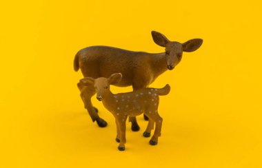 Oyuncak doe ve plastik sarı bir arka plan üzerine açık kahverengi. Bir çocuk için orman hayvan.