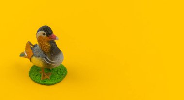 Sarı bir arka plan üzerinde plastik oyuncak mandarin ördeği. Hayvanlarıyla bir çocuk için. Yazmak için bir yer.