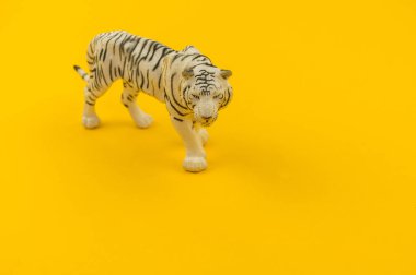 Plastik sarı bir arka plan üzerinde beyaz albino kaplan oyuncak. Hayvanlarıyla bir çocuk için.