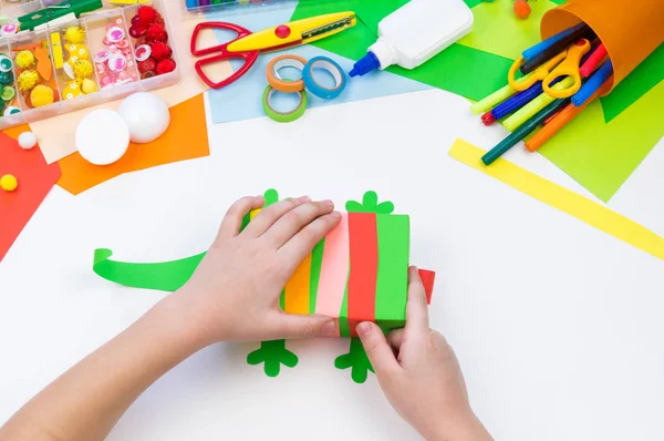 Child makes a hack box chameleon. Material for creativity on a white background. — Stock Photo, Image