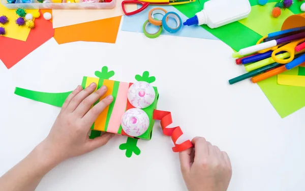 Child makes a hack box chameleon. Material for creativity on a white background. — Stock Photo, Image