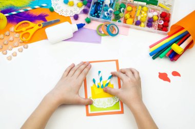Çocuk pasta resmi olan bir kartpostal yapar. Çocuk evrak.