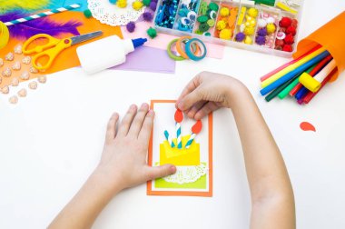 Çocuk pasta resmi olan bir kartpostal yapar. Çocuk evrak.