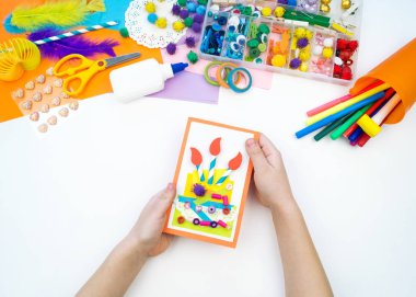 Çocuk pasta resmi olan bir kartpostal yapar. Çocuk evrak.