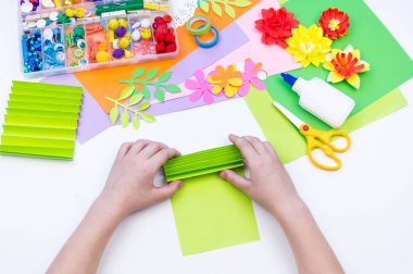 Çocuk bahar tatili için anneye bir hediye yapar. Kağıttan yapıştırılmış çiçek.