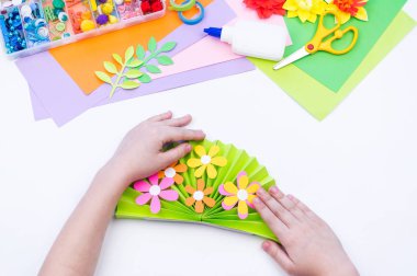 Çocuk bahar tatili için anneye bir hediye yapar. Kağıttan yapıştırılmış çiçek.