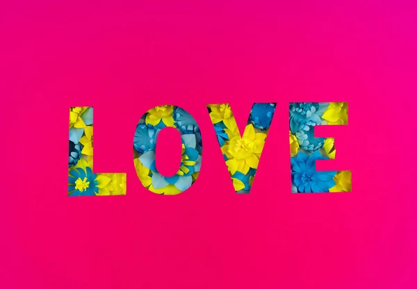 Inscriptie liefde gesneden uit papier, in de bloem gemaakt van papier. Roze achtergrond. — Stockfoto