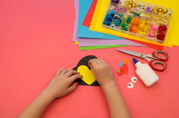Pinguin aus Papier auf rosa Hintergrund. Werkstatt. Kinderhände kleben Bastelarbeiten. — Stockfoto