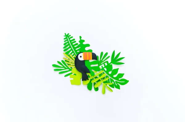 Decorative Arrangement of tropical leaves and flowers. Toucan bird made of paper. — Stock Photo, Image