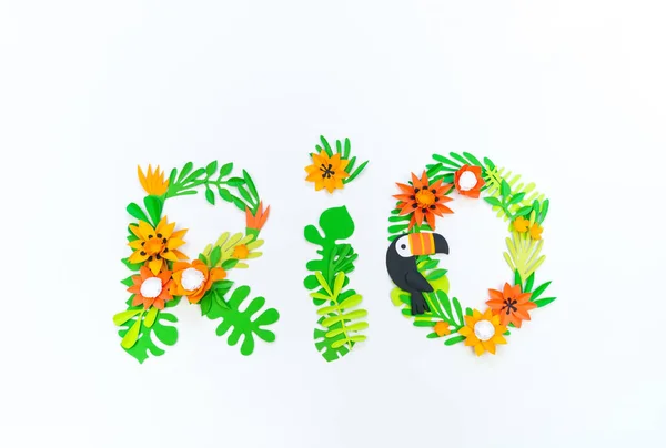 Word rio Decorative Arrangement of tropical leaves and flowers. Toucan bird made of paper. — Stock Photo, Image