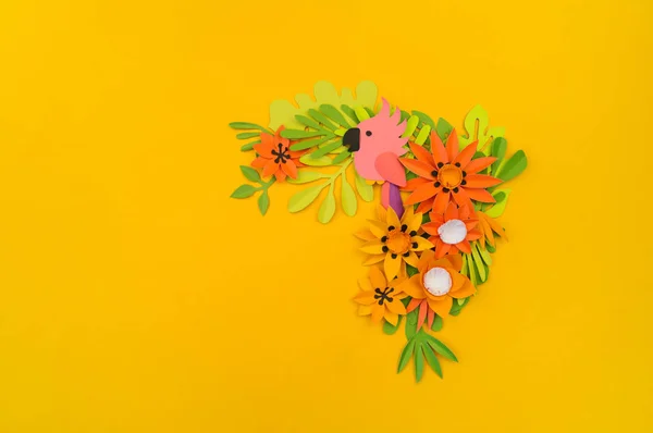 熱帯の葉と花の装飾的な組成。ペーパークラフト。黄色の背景。ピンクのオウム. — ストック写真