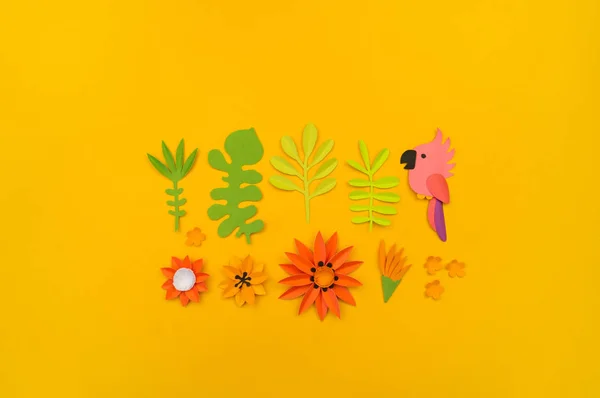 Dekorative Komposition aus tropischen Blättern und Blüten. Papierbasteln. gelber Hintergrund. rosa Papagei. — Stockfoto
