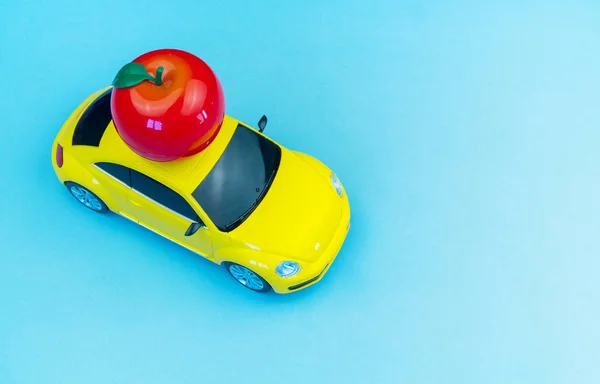 Игрушечный автомобиль несет на крыше канцелярские принадлежности для школы.Apple — стоковое фото