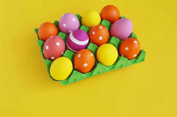 Easter eggs in a tray for eggs a stand. Yellow background. — Stock Photo, Image