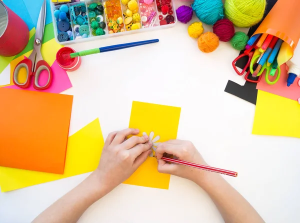 Child cuts a flower from paper. Origami paper plastic. Favorite hobby toy. — Stock Photo, Image