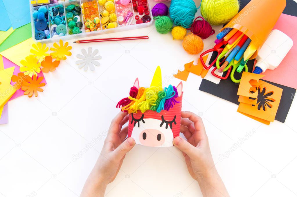 child makes a hand-made unicorn out of a tin can. Rainbow hair