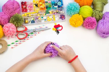 Çocuk bir favori hobi meşgul. Çocuk yünlü iplik canavarından ponpon yapıyor. Tatil oyuncak hediye.
