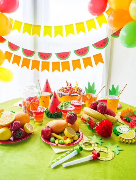 Decoración para unas vacaciones de cumpleaños de los niños. Fiesta de frutas. Pastel y dulces dulces. Vajilla desechable y frutas tropicales . —  Fotos de Stock