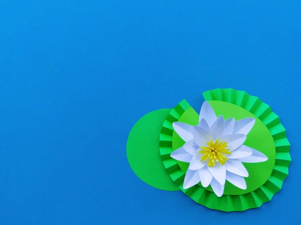 Waterlily flower made of paper. Blue background. Origami hobby. Gentle petal. Copy spase