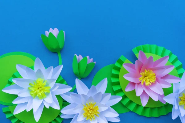 Waterlily flower made of paper. Blue background. Origami hobby. Gentle petal.