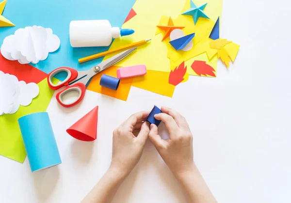 Manos del niño hacen un cohete artesanal de papel. nubes de cosmos y estrellas de papel de color. El proceso creativo — Foto de Stock