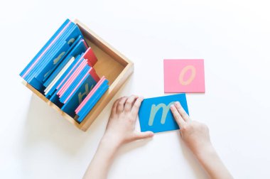 Montessori malzemesi. Çocukların elleri. Mektup ve kelimelerin incelenmesi. Kaba alfabe işgali