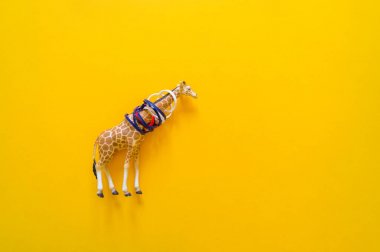 Plastik içinde Afrika hayvan zürafası. Çöpten muzdarip. Sarı arka plan.