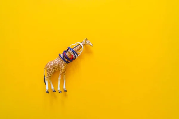 Girafa animal africana em plástico. Sofre de lixo. Fundo amarelo . — Fotografia de Stock