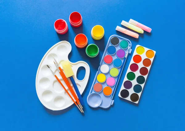 Papelería en posición plana. Material para el dibujo y el artista se encuentra sobre un fondo azul . —  Fotos de Stock