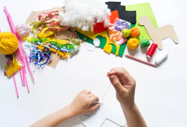 Las manos del niño diy hacen lama de juguete artesanal. Fieltro suave artesanía . —  Fotos de Stock