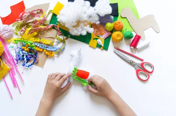 The hands of the child diy do handicraft toy lama. Felt soft craftsmanship. — Stock Photo, Image