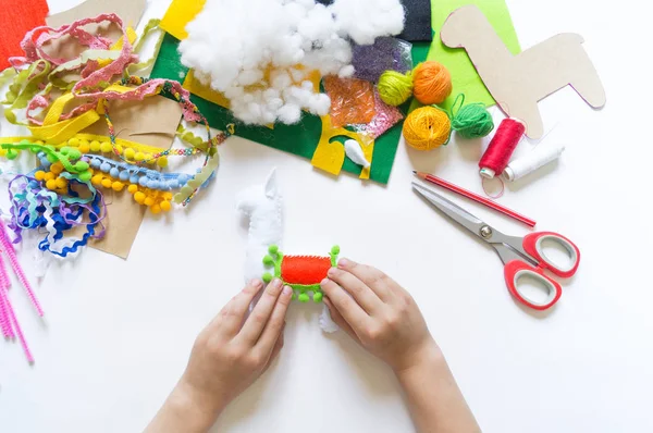 Les mains de l'enfant bricolage faire lama jouet artisanal. Feutre artisanat doux . — Photo