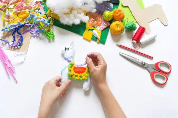 Las manos del niño diy hacen lama de juguete artesanal. Fieltro suave artesanía . — Foto de Stock