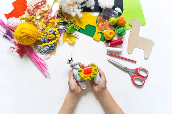 Die Kinderhände basteln Spielzeug-Lama. Filz weiche Verarbeitung. — Stockfoto