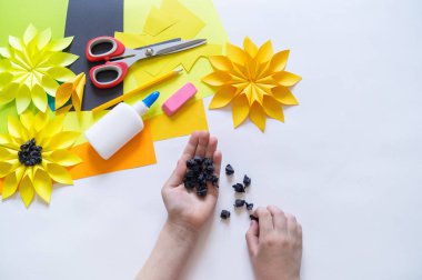 çocuğun elleri ayçiçeğinden garip bir çiçek kağıdı yapar. Sarı bitki yaz. Yaratıcı süreç.