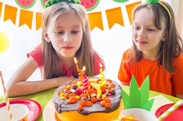 Las chicas celebran su cumpleaños. El niño apaga las velas del pastel. Fiesta de frutas. Piña y sandía . —  Fotos de Stock