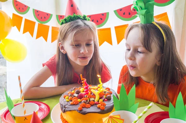 Las chicas celebran su cumpleaños. El niño apaga las velas del pastel. Fiesta de frutas. Piña y sandía . — Foto de Stock