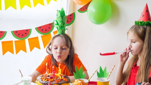 Dziewczęta świętować swoje urodziny. Dziecko wieje świece na torcie. Partia owocowa. Ananas i arbuz. — Zdjęcie stockowe