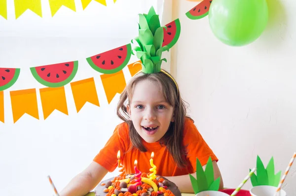 Las chicas celebran su cumpleaños. El niño apaga las velas del pastel. Fiesta de frutas. Piña y sandía . —  Fotos de Stock