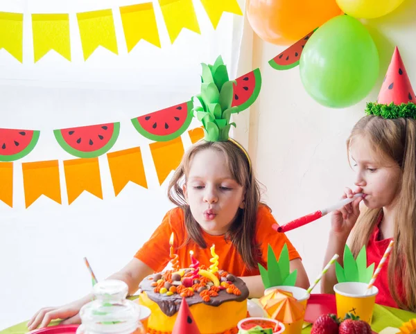 Las chicas celebran su cumpleaños. El niño apaga las velas del pastel. Fiesta de frutas. Piña y sandía . —  Fotos de Stock