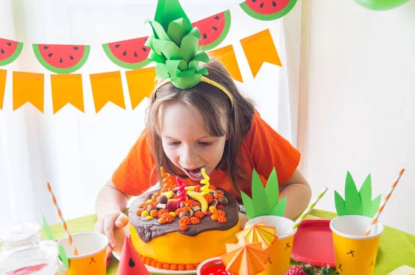 La chica muerde todo un pastel de cumpleaños. Los niños celebran un cumpleaños. Fiesta de frutas. Vacaciones infantiles . —  Fotos de Stock