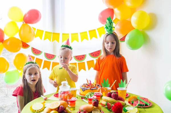 A gyermekek születésnapját ünneplik. A gyermek felrobban a gyertyák a tortán. Gyümölcs-Party. — Stock Fotó