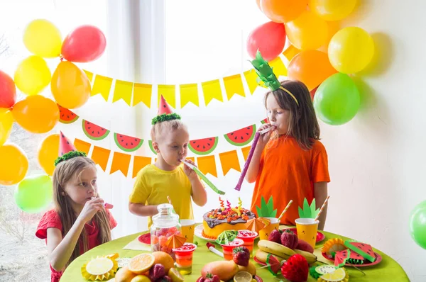 Los niños celebran un cumpleaños. El niño apaga las velas del pastel. Fiesta de frutas . —  Fotos de Stock
