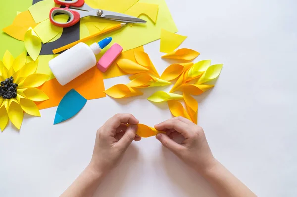 Manos del niño hace un papel de flores extraño de girasol. Planta amarilla verano. El proceso creativo . — Foto de Stock