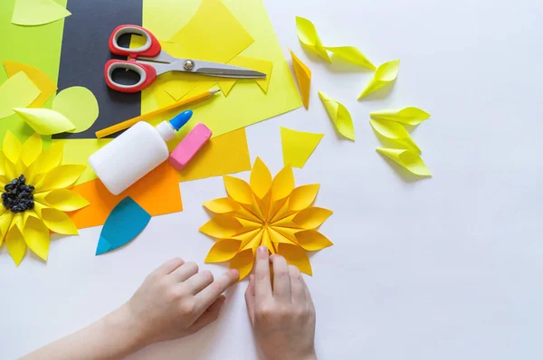 Manos del niño hace un papel de flores extraño de girasol. Planta amarilla verano. El proceso creativo . — Foto de Stock