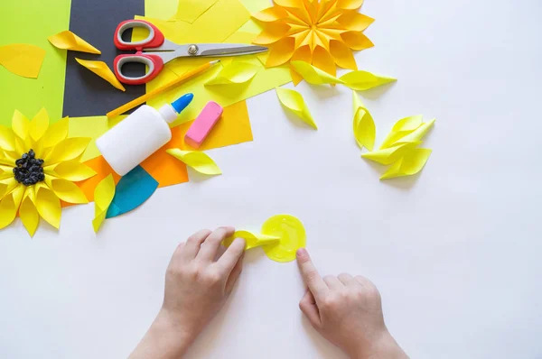 아이의 손은 해바라기에서 이상한 꽃 종이를 만든다. 노란색 식물 여름입니다. 크리에이티브 프로세스. — 스톡 사진