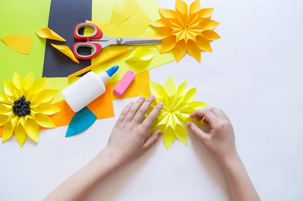 Ruce dítěte dělají z slunečnice podivný květinový papír. Žluté rostliny v létě. Kreativní proces. — Stock fotografie