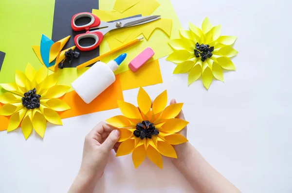 Mâinile copilului fac o hârtie de flori ciudată din floarea soarelui. Vara plantelor galbene. Procesul creativ . — Fotografie, imagine de stoc